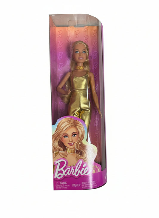 Barbie doll in a gold dress in its packaging on a white surface
