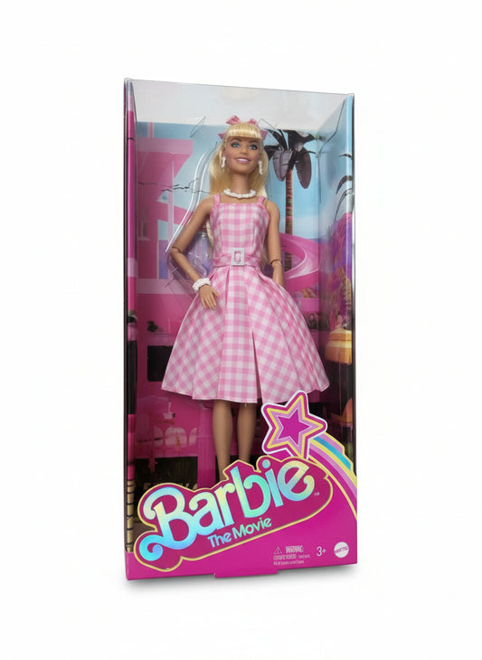 Barbie doll packaging with a pink dress on a wooden surface